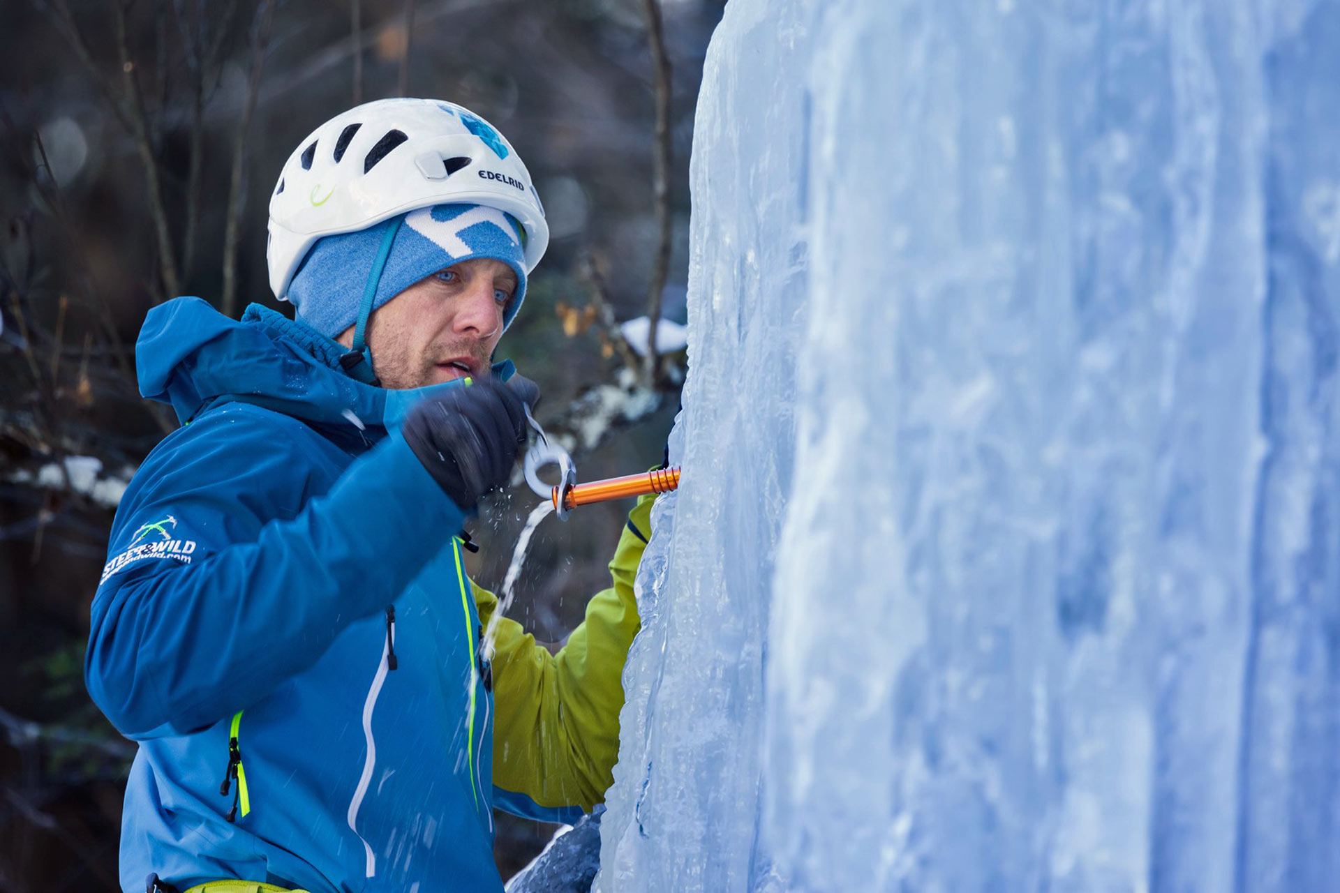 Kletterer dreht eine Eisschraube beim Eisklettern in Eis Kletterer dreht eine Eisschraube beim Eisklettern in Eis